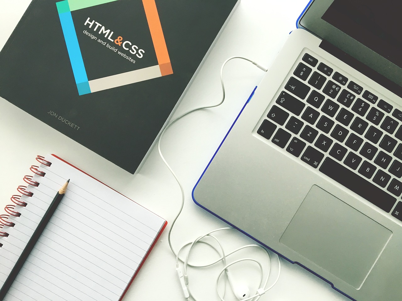 a laptop, notebook, pencil, and book of web designing